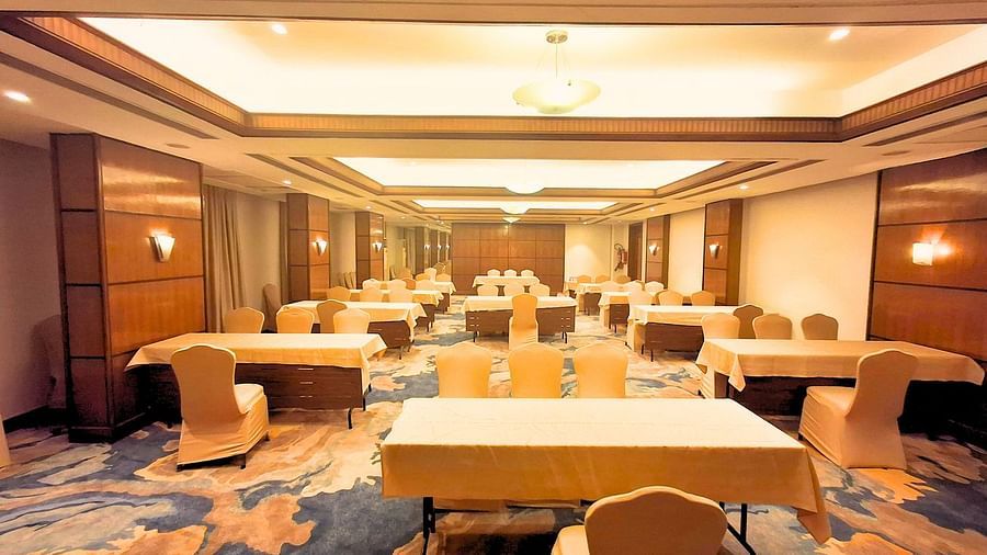 A spacious banquet hall at Pride Plaza Ahmedabad, featuring multiple tables set up for a conference or event.